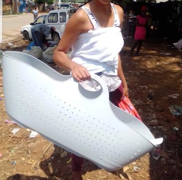 Person carrying a large white plastic basket outdoors.