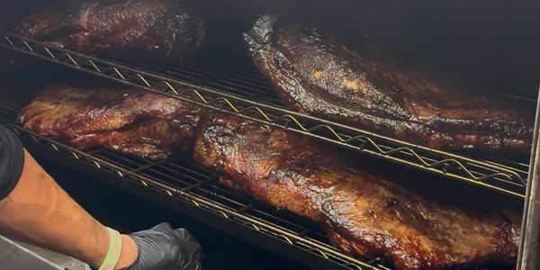 Large slabs of meat smoking on racks inside a smoker.