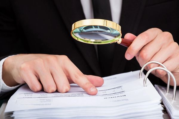 Businessman Looking At Document Through Magnifying Glass