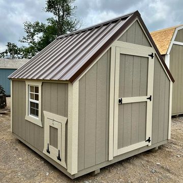 A small beige wooden shed with a brown metal roof and a window.
