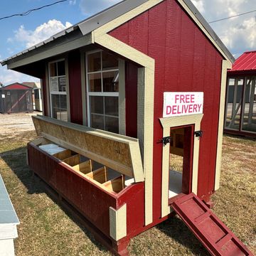Red and cream chicken coop with free delivery sign and storage compartments.