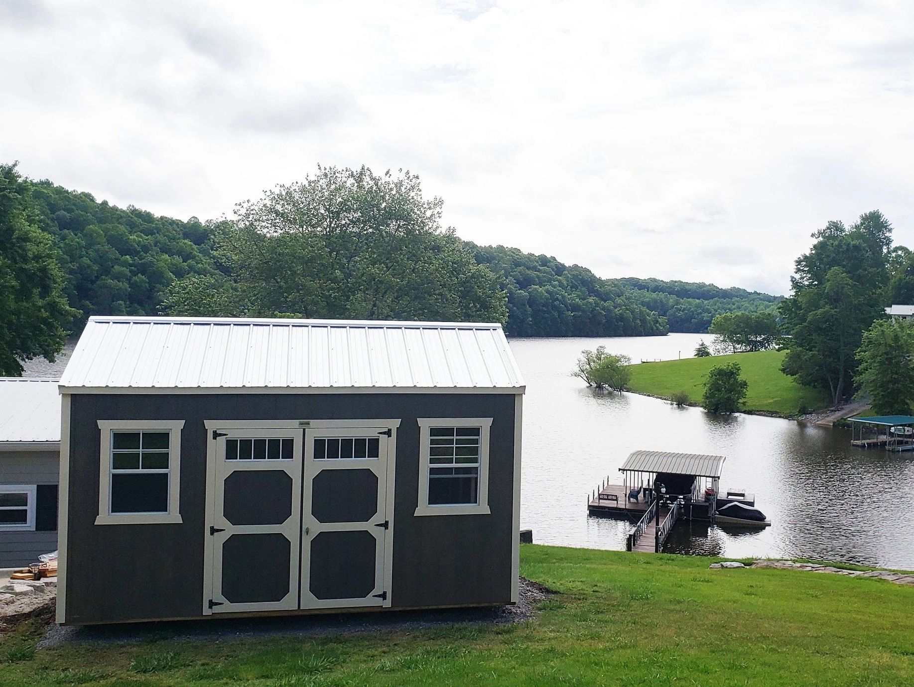 Small shed by a lakeside with a dock and boat.