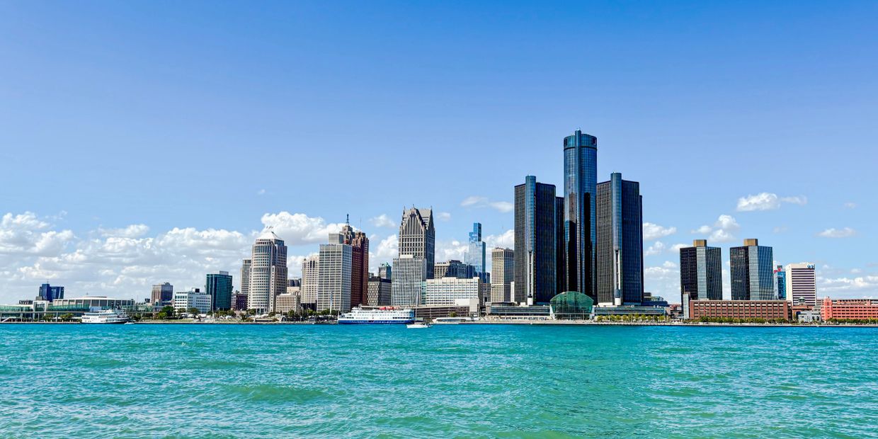 Detroit skyline with clear blue skies and water in foreground.