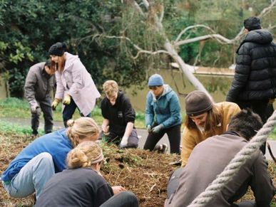 A group of people gardening together outdoors in a natural setting.