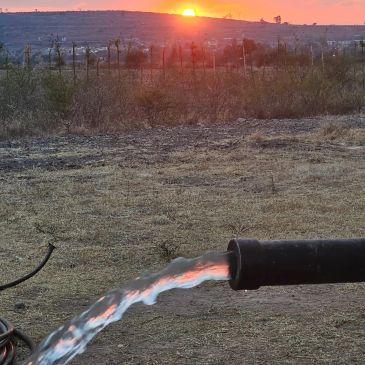 Agua fluyendo de una tubería al atardecer.