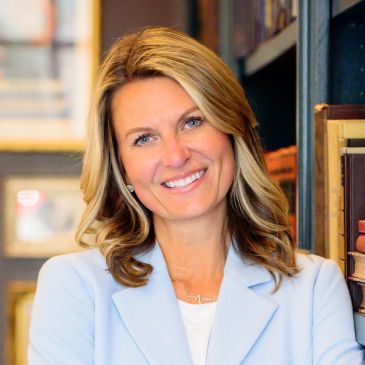 Smiling woman with blonde hair in a light blue blazer.