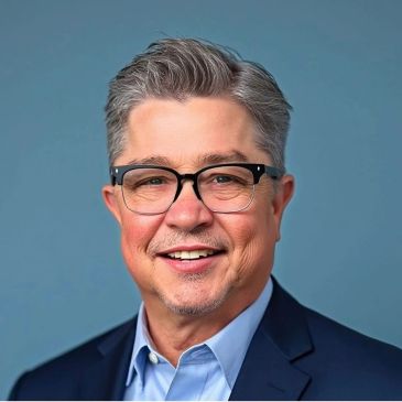 Smiling middle-aged man with glasses and gray hair.