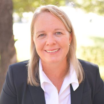 Smiling woman in business attire outdoors.