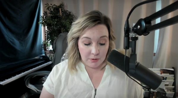 Woman speaking into a microphone in a home studio setup.