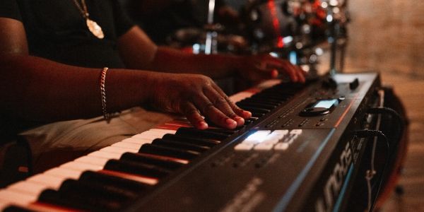 Hands playing an electronic keyboard in a dimly lit setting.