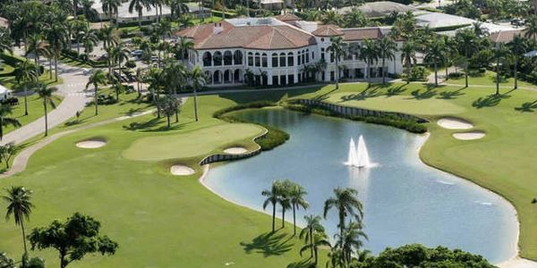 A luxurious golf course with a water fountain and clubhouse.