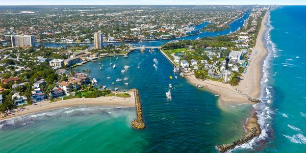 Aerial view of a coastal city with boats and a waterway leading to the ocean.