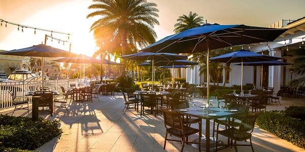 Outdoor patio dining area with tables, chairs, and umbrellas at sunset.