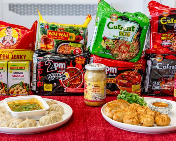 Assorted instant noodles and momos displayed with cooked momos and dipping sauces.
