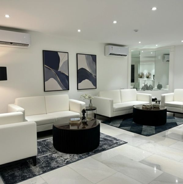 Modern living room with white sofas and dark coffee tables on patterned rugs.