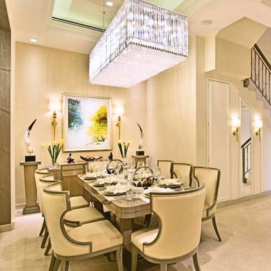 Elegant dining room with a large crystal chandelier and beige chairs.