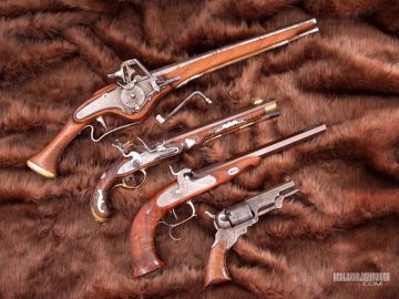 Four vintage pistols displayed on a fur background.