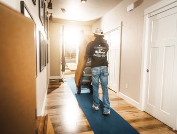 Bend Brothers Moving Mover taking boxes out of a home on hand truck over floor protection