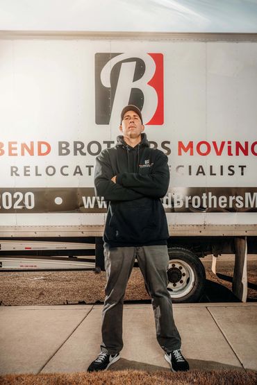Owner of Bend Brothers Moving, proudly standing in front of moving truck displaying company name