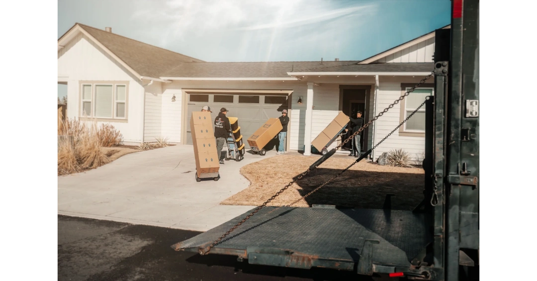 movers with hand trucks taking boxes and totes into a home