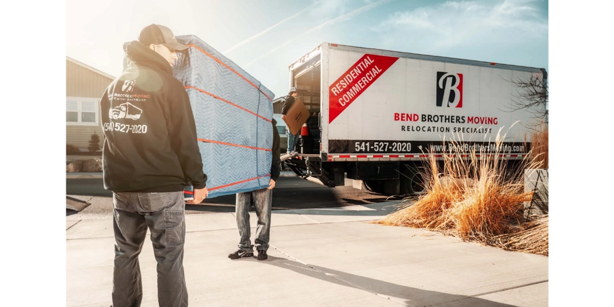 Bend Brothers Moving Movers Carrying furniture to a moving truck. Furniture is covered in moving pad