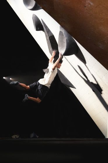Man climbing a steep indoor rock wall, captured mid-jump.