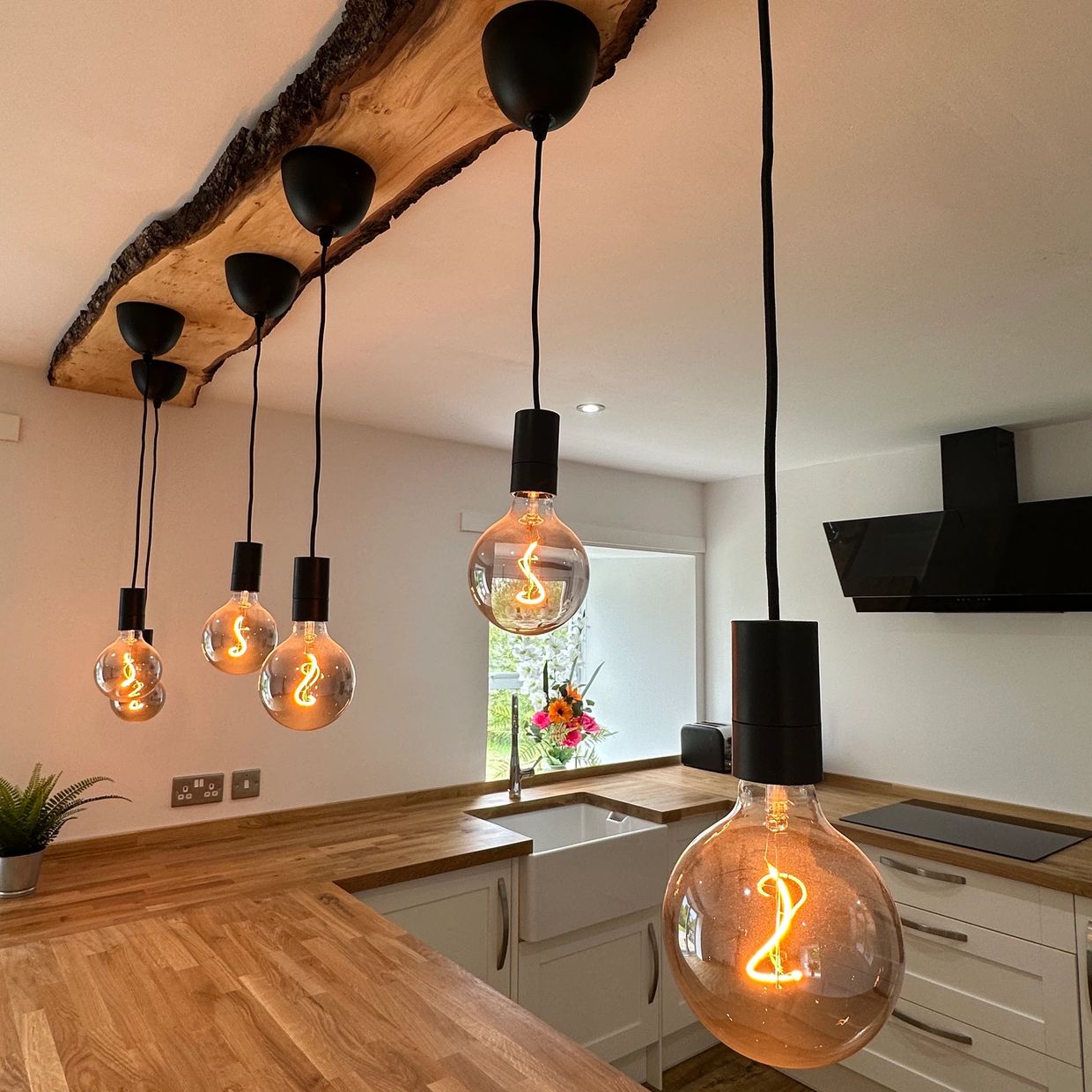 Modern kitchen with wooden countertops and hanging Edison bulbs.