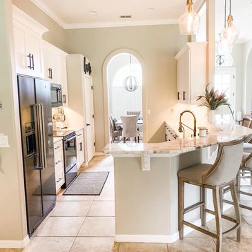 White kitchen with white cabinets and an archway leading to a dining room.