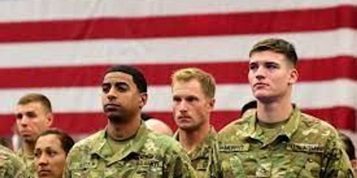 Young soldiers in uniform standing under a flag.