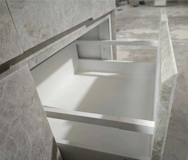Open marble drawer with white interior in a kitchen or bathroom setting.