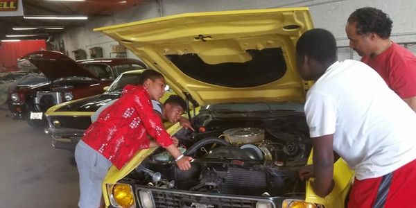 Young adults with a mentor learning about an engine.