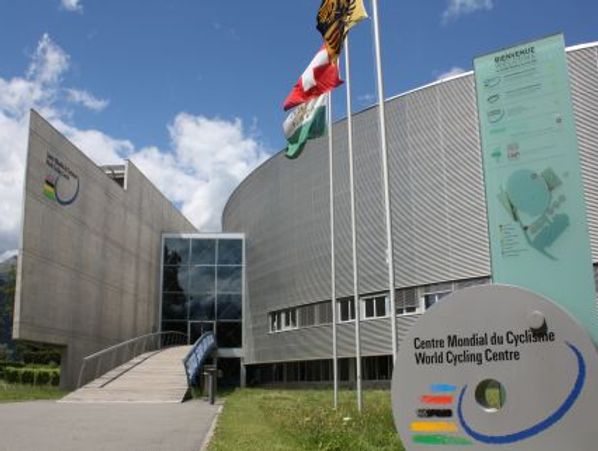 Modern building of the World Cycling Centre with flags and signage.
