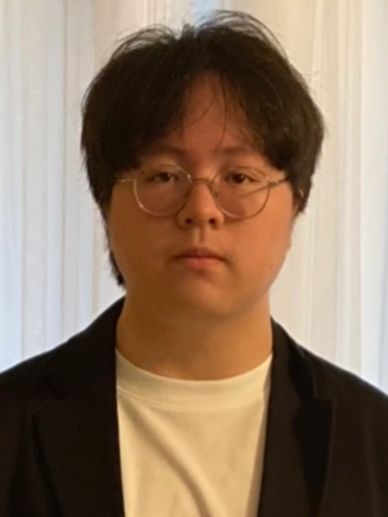 Portrait of a young man wearing round glasses and a black blazer over a white shirt.
