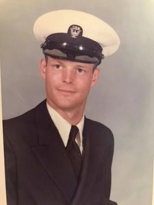 Portrait of a young man in a Navy uniform with a white hat and black suit.
