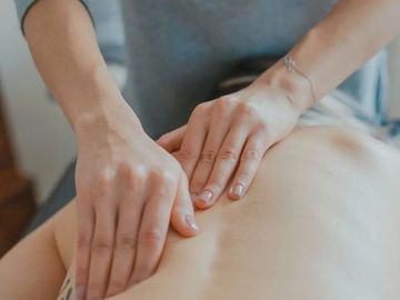 Hands giving a back massage with gentle pressure.