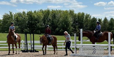 Three horseback riders and an instructor at an equestrian area.