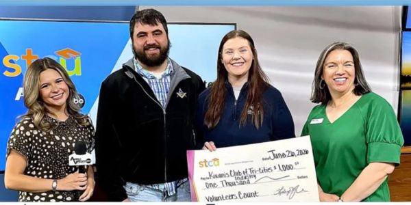 Four people presenting a large check for one thousand dollars.