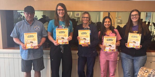 Five people holding coloring books and smiling.