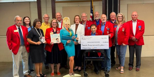 Group of people presenting a large check indoors.