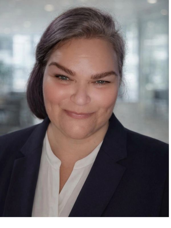 Confident woman in business attire smiling warmly.