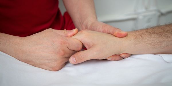 A massage therapist works on a patient's hand. This is a hand massage.