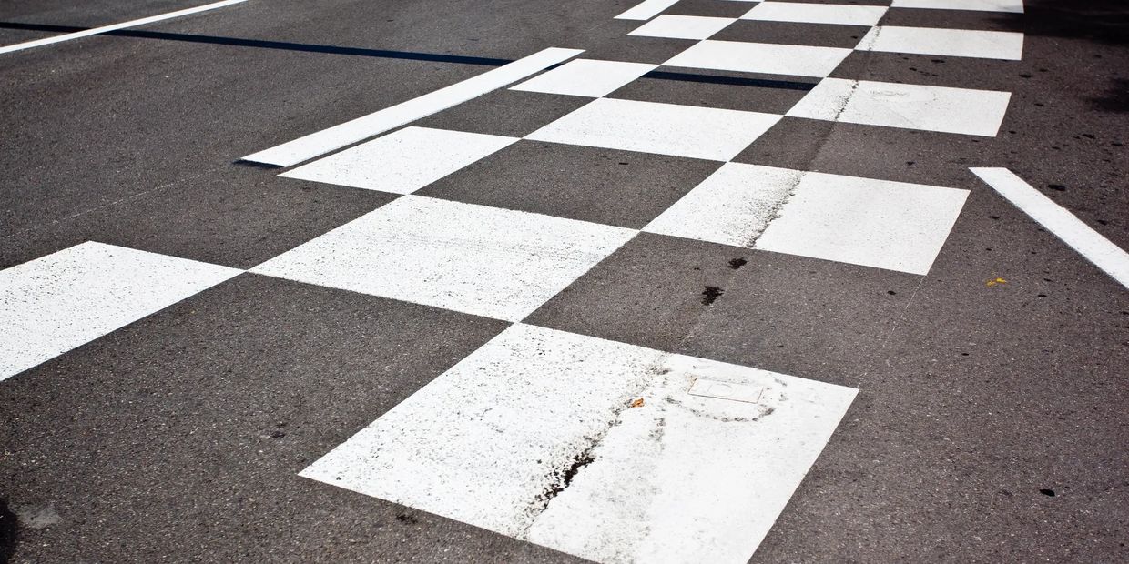 A white checkered finish line on asphalt road.