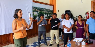 Mujer hablando frente a grupo en reunión.