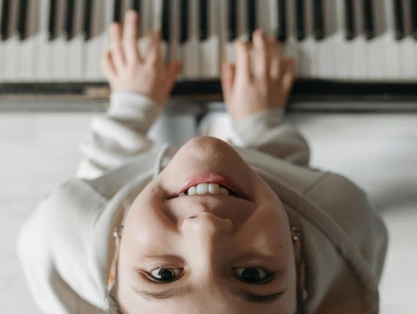 Smiling person playing piano, viewed from above.