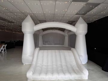 A large white inflatable bounce house under string lights indoors.