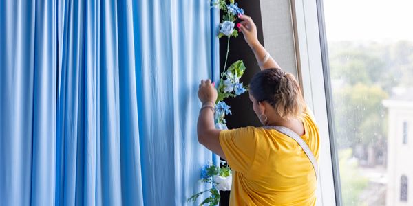 Person decorating with blue flowers by a window.