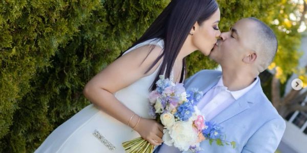 Couple kissing with a bouquet in hand.