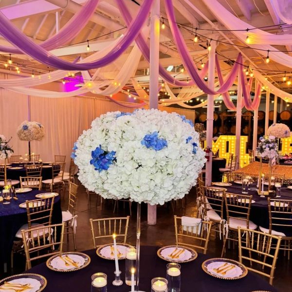 Elegant wedding reception setup with floral centerpieces and draped ceiling fabric.