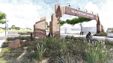 Entrance archway to the Beachfront District with landscaping and people walking.
