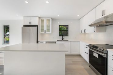 Modern white kitchen with stainless steel appliances and a large island.